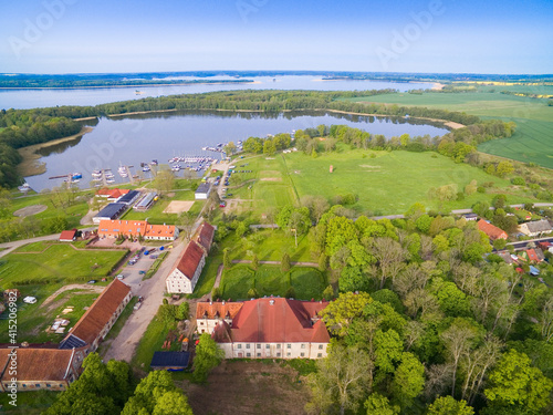 Ruined Baroque style palace in Sztynort, Poland (former Steinort, East Prussia). Sztynorckie Lake and yachts moored in marina in the background photo