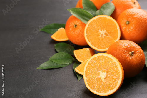 Delicious ripe oranges on black table. Space for text