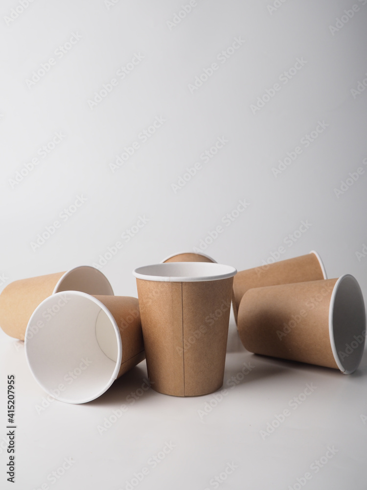 Several paper disposable brown cups are randomly placed on a white background Several paper disposable brown cups are randomly placed on a white background