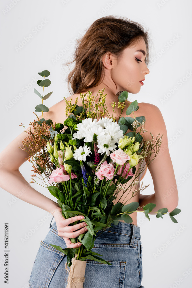 Back view of shirtless model holding bouquet isolated on grey