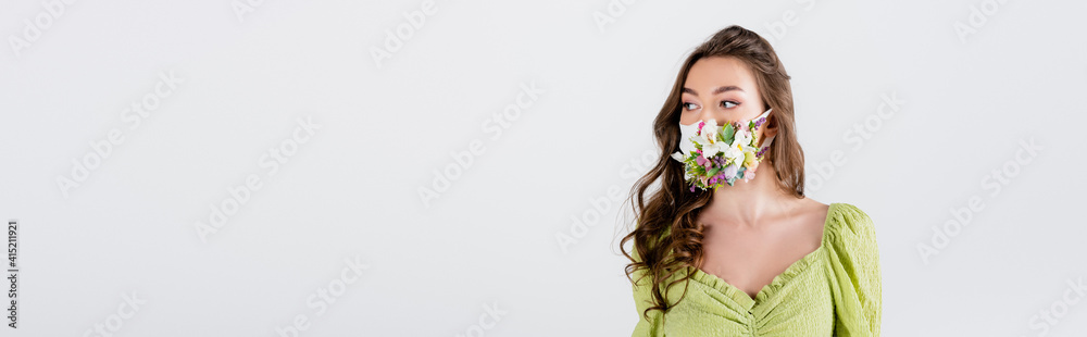 Brunette woman in medical mask with flowers looking away isolated on grey, banner Brunette woman in medical mask with flowers looking away isolated on grey, banner