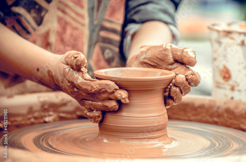 Hands of a potter at work. Potter making ceramic mug on the pottery wheel