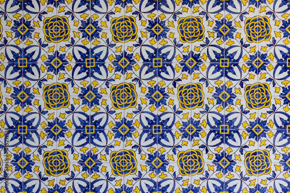 blue and yellow handmade tiles with floral pattern on facade in lisbon