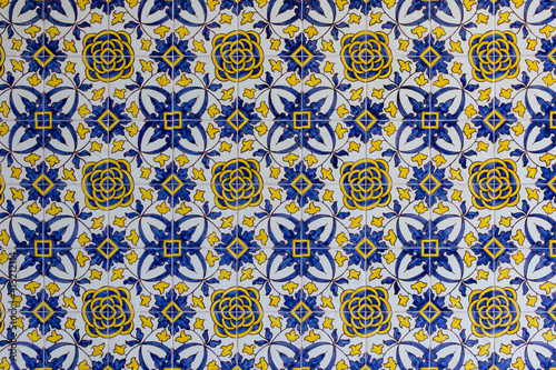 blue and yellow handmade tiles with floral pattern on facade in lisbon