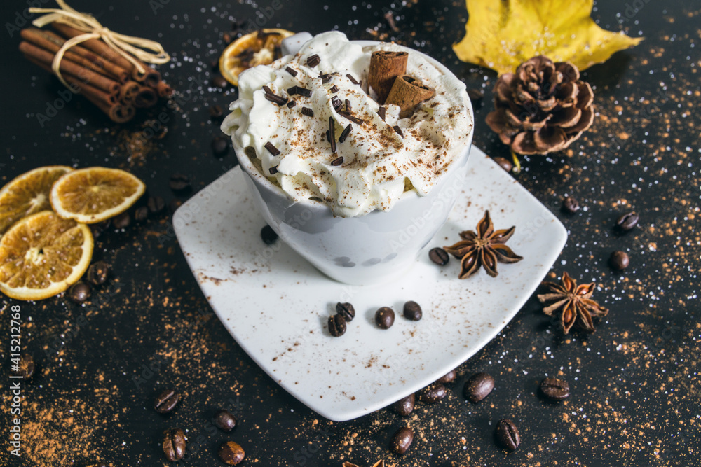Cup of coffee with cinnamon sticks, whipped cream, chocolate sprinkles and star anise. Cozy winter or autumn hot beverage composition. Cup of coffee with cinnamon sticks, whipped cream, chocolate sprinkles and star anise. Cozy winter or autumn hot beverage composition.