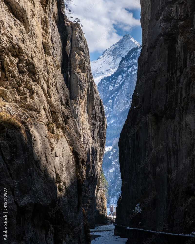 view of snow covered mountain from a narrow dark canyon in switzerland