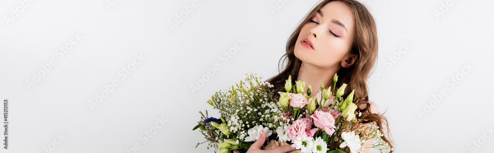 Young woman with closed eyes holding bouquet isolated on grey, banner