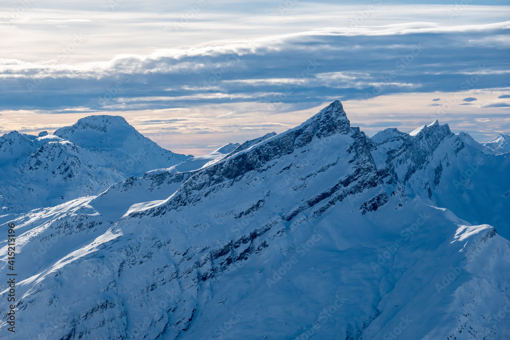 beautiful snow covered mountain peak with cloud lines in the sky at sunset swiss alps