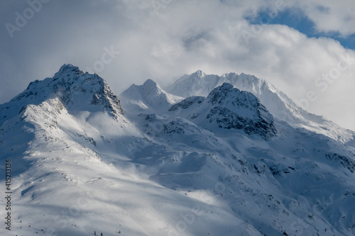 snow covered mountains in the clouds lit by soft sunlight