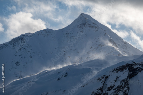 snowy mountain peak veiled in clouds and wind