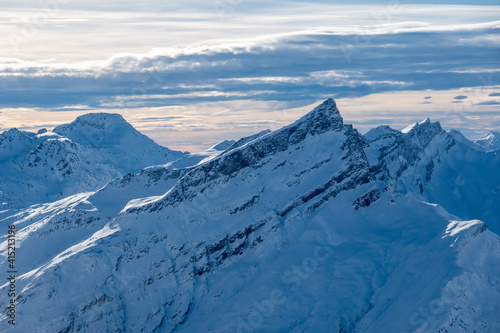 beautiful snow covered mountain peak with cloud lines in the sky at sunset swiss alps