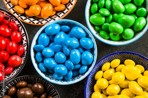 M&M's candy on the black background in bowls, colorful candy, multicolored gradient