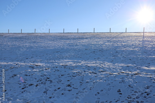Beautiful blue sky and a very bright sun over a white frozen dike landscape.