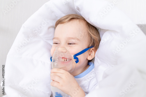 sick baby boy with inhaler treats throat at home  the concept of health and inhalation treatment