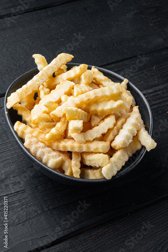 Frozen French fries potatoes, on black wooden table background