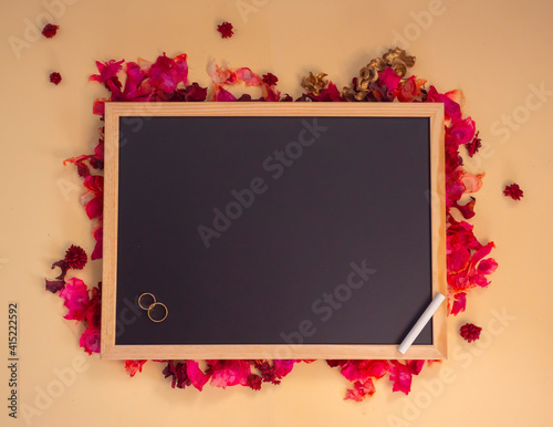 Pizarra sobre fondo de flores con anillos de boda