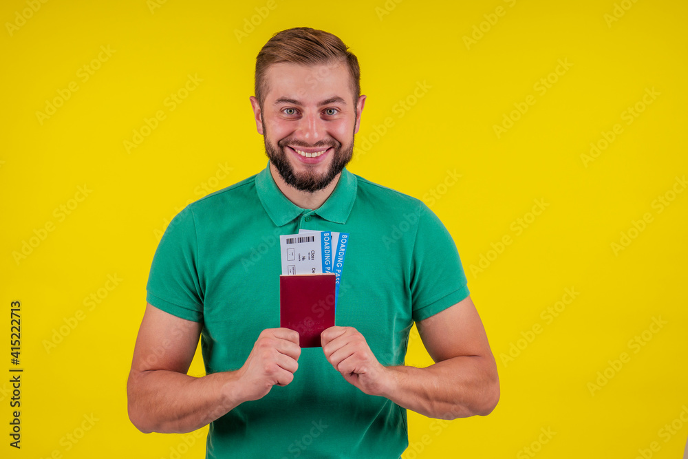 ortrait of a happy young man in sunglasses and green t-shirt holding passport isolated over yellow background ortrait of a happy young man in sunglasses and green t-shirt holding passport isolated over yellow background