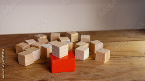 wooden block on a red block around another wooden block. Nomination concept.