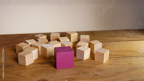 Purple block surrounded by organised wooden block meaning cooperative cooperation. leadership and teamwork concept