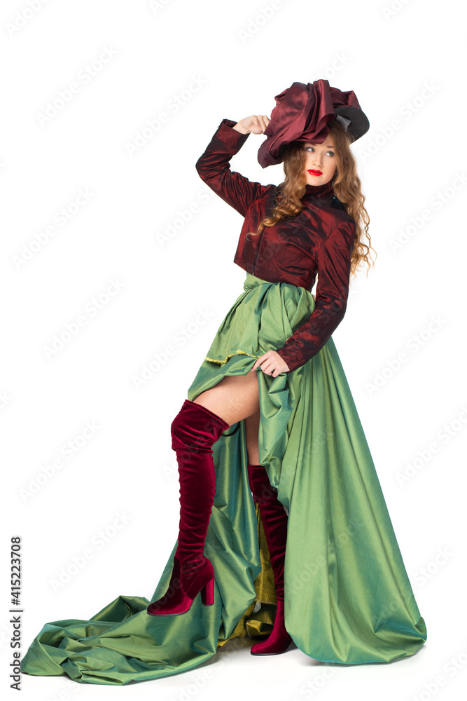 Fashion photo of a beautiful elegant young teenager girl with long curly hair in a pretty long green skirt and high boots isolated on white background.