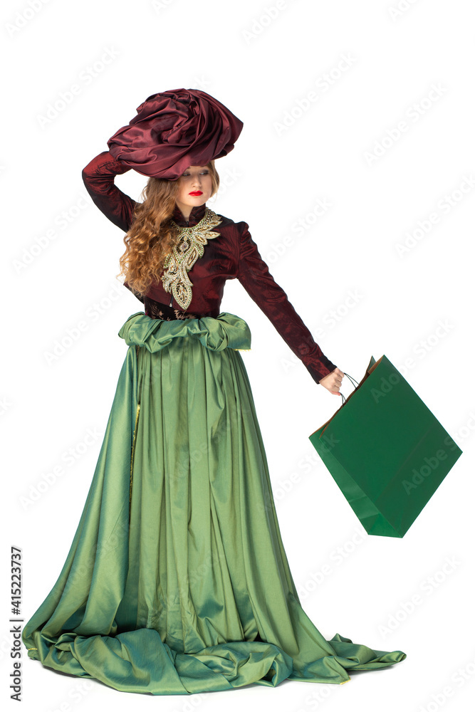 Fashion photo of a beautiful elegant young teenager girl with long curly hair and with paper bag, in a pretty long green skirt isolated on white background.