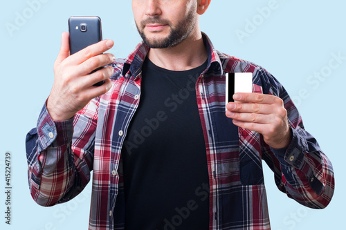 A man holds a bank card and a smartphone in his hand © Ivan