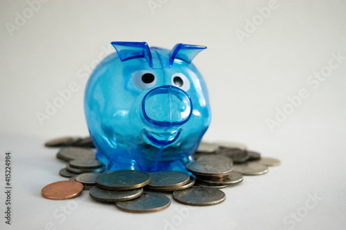 Blue piggy bank with money coins isolated on white background