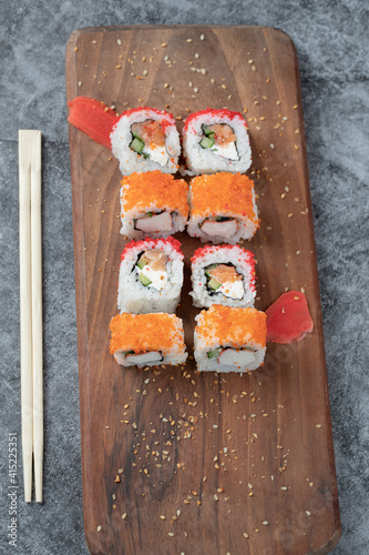 Maki rolls with red caviar topping on a wooden platter