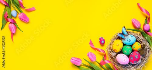 Canvas Print Easter - Colorful Eggs In Nest With Butterfly And Pink Tulips In Yellow Backgrou