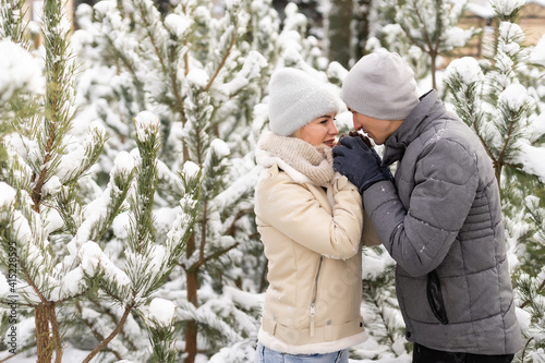 happy loving couple walking in snowy winter forest, spending christmas vacation together. Outdoor seasonal activities. Lifestyle