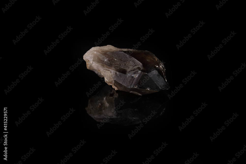 Close-up of smoky quartz stone from Ural region, Russia on black glass background. Rauchtopaz crystal on black glass background.