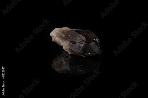 Close-up of smoky quartz stone from Ural region, Russia on black glass background. Rauchtopaz crystal on black glass background.