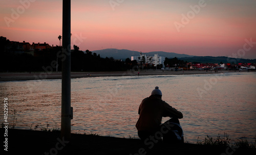sad man alone in a beach at sunset time