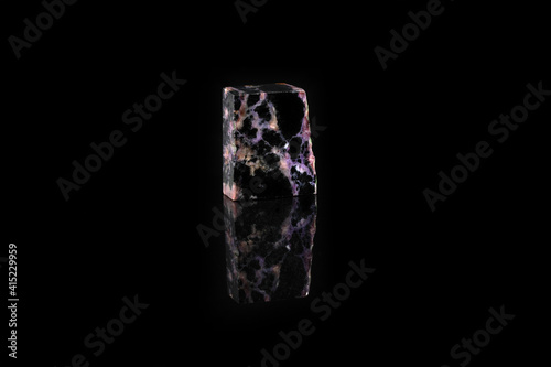 Natural mineral stone - polished charoite gemstone on black glass background. photo