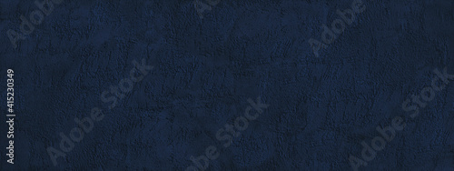 Navy blue abstract background. Dark blue toned texture of a rough plastered concrete wall. Monochrome background with copy space for design. Wide banner.