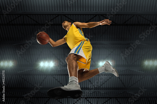 Young professional basketball player in action, motion isolated on black background, look from the bottom. Concept of sport, movement, energy and dynamic, healthy lifestyle. Training, practicing. © master1305