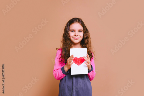 Happy family daughter girl kid giving a greeting card on holiday isolated on a beige background. Father's day. Mother's Day. Valentine's Day.
