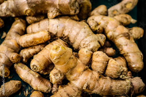 Pile of raw ginger root on dark background - Selective focus.