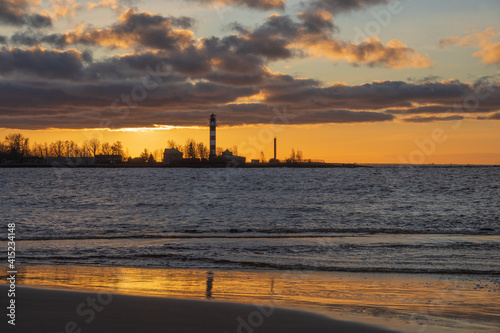 View to the Daugavgriva lighthouse from Mangalsala pier against colorful sunset sky
