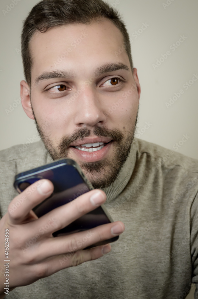 Portrait of an amused young man who is recording an audio message on his smartphone Portrait of an amused young man who is recording an audio message on his smartphone
