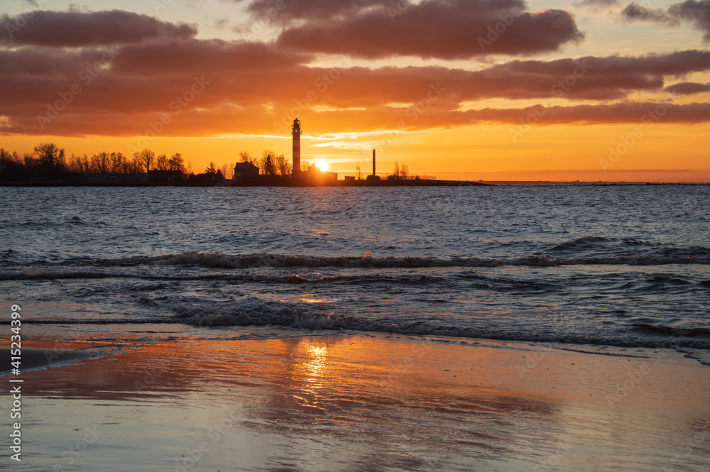 View to the Daugavgriva lighthouse from Mangalsala pier against colorful sunset sky