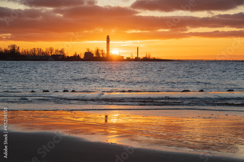  View to the Daugavgriva lighthouse from Mangalsala pier against colorful sunset sky 