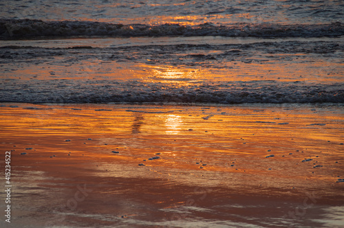 Shoreline of the sea with orange reflection of sunset sky