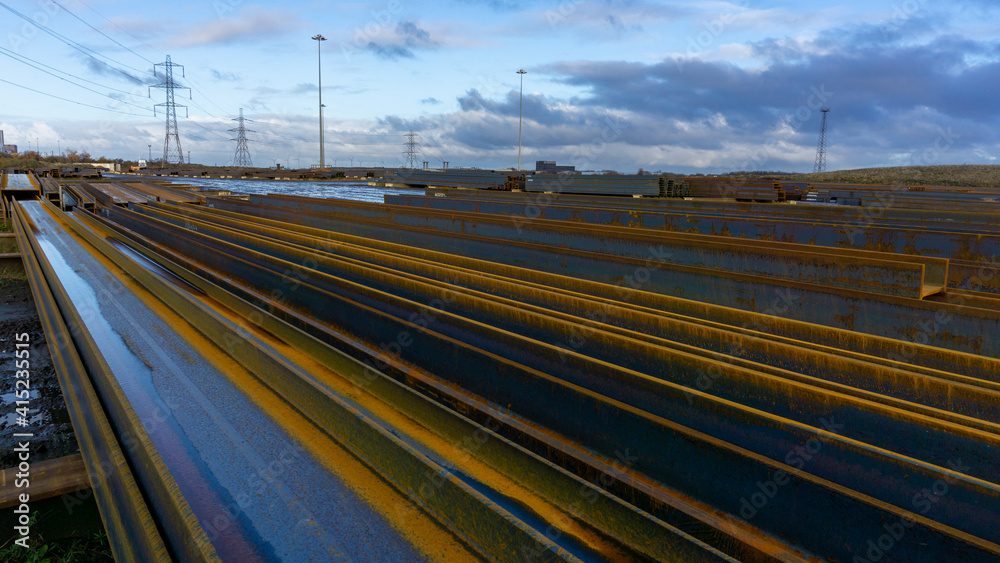 Rusting Steel Girders lay in Piles in a Large Manufacturing Plant Ready for Shipping.