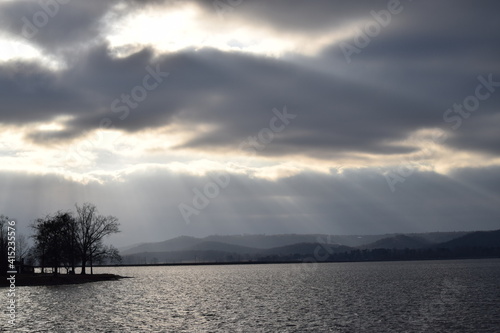 sun through clouds over lake