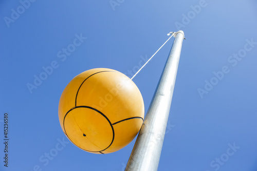 Canvas Print A view looking up at a tetherball attached to a metal pole, against a blue clear sky