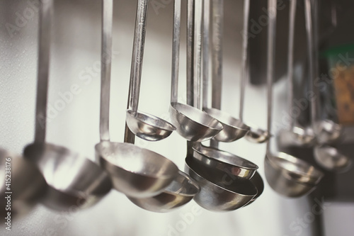 A view of several metal ladles hanging in a kitchen setting.