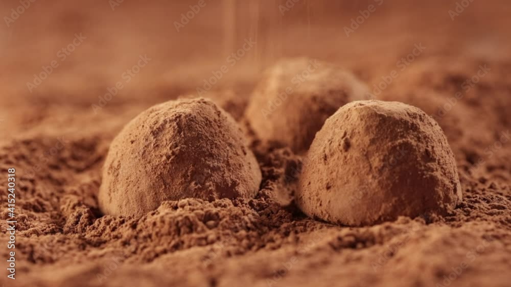 cocoa powder is poured on chocolate truffles, slow motion close up macro cocoa powder is poured on chocolate truffles, slow motion close up macro