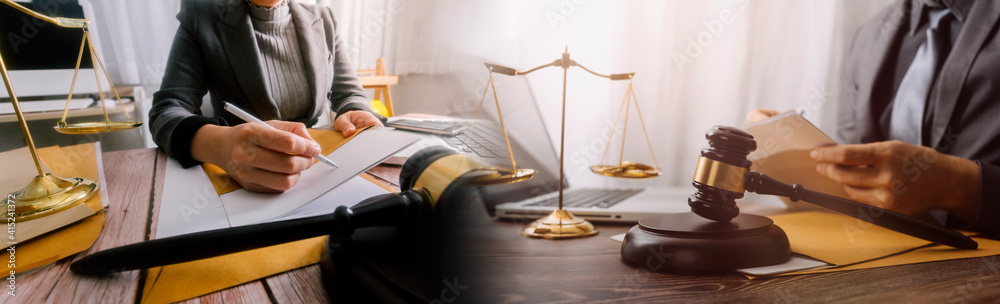 Justice and law concept.Male judge in a courtroom with the gavel, working with, computer and docking keyboard, eyeglasses, on table in morning light