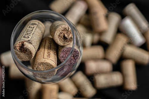 Bunch of wine corks and a glass over a black blanket 